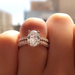 A close-up shot of a 1ct oval diamond ring set in rose gold, paired with matching pavé diamond bands, sparkling under natural sunlight for a luxurious, radiant effect.
