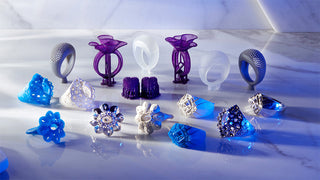 A jewelry designer using CAD software on a computer, with 3D-printed ring prototypes and gemstone models on the desk—showcasing how technology is transforming modern jewelry creation.