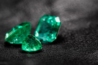 Close-up of a vivid green Zambian emerald gemstone set in a gold ring under natural light