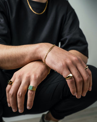 Well-dressed man adjusting his bracelet and rings, showcasing stylish yet balanced jewelry choices that reflect personal style.
