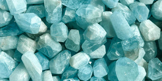 A close-up of a sparkling aquamarine gemstone, showcasing its light blue color and brilliance.