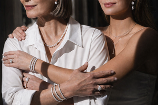 Elegant close up of two women’s hands layered with diamond rings and bracelets showing heirloom inspired jewelry styling