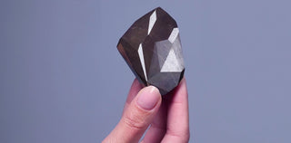 Close-up of a faceted black diamond ring glowing under soft lighting with a mysterious sparkle