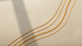 Jeweler repairing a broken gold chain using precision tools on a workbench.