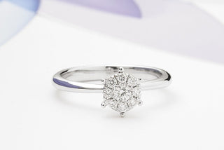 A close-up of a solitaire effect engagement ring, where smaller diamonds are cleverly set around a center stone to create the illusion of one large diamond- showcasing brilliance and smart design.