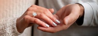 Close-up of a diamond ring with prong setting beside a sleek bezel-set gemstone ring on a neutral background