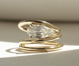 A sparkling moissanite engagement ring in a custom setting, glowing under natural light on a neutral-toned fabric backdrop.  