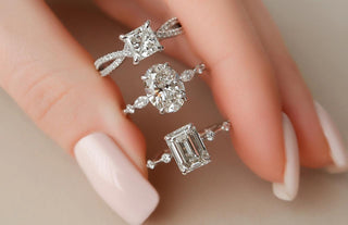 Three sparkling center stones - lab diamond, moissanite, and natural diamond - displayed side by side on a ring tray for comparison. 
