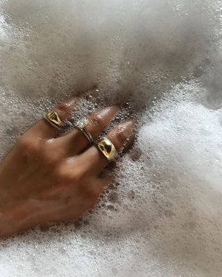 Flat lay of gold and silver jewelry beside common cleaning products, illustrating jewelry care dos and don’ts.