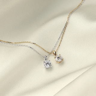 Close-up of a classic diamond pendant necklace resting on a soft fabric, radiating elegance and timeless beauty.