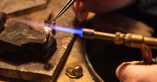 A craftsman working at a jewelry bench, transforming old rings and broken chains into a new, custom-designed necklace—illustrating the creative process of repurposing vintage jewelry into modern pieces.