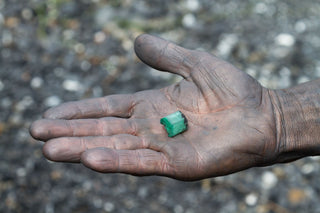 An open-pit mine with heavy machinery extracting earth, surrounded by deforested land—illustrating the environmental toll of mining for precious metals and gemstones, including habitat loss and soil disruption.