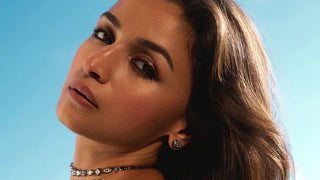 Alia Bhatt posing under the Cannes sky in 2025, wearing inverted pear diamond studs and a statement diamond choker, styled with soft waves and radiant bronze makeup