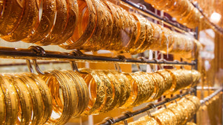 A fluctuating gold price chart beside gold bars and coins, illustrating market trends and optimal buying times.