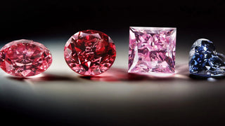 Collection of rare fancy-colored diamonds, including oval and round pink diamonds, a princess-cut pink diamond, and a heart-shaped blue diamond, displayed under studio lighting.