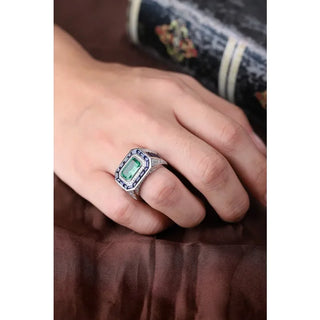 Azzallure Emerald Tempest Ring featuring a 3.18-carat emerald green lab sapphire, surrounded by blue and silver lab stones in a sterling silver diamond-style setting.
