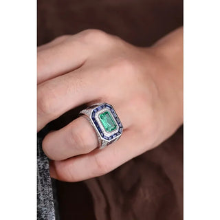 Azzallure Emerald Tempest Ring featuring a 3.18-carat emerald green lab sapphire, surrounded by blue and silver lab stones in a sterling silver diamond-style setting.
