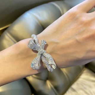 Empress Bow Bangle in 925 sterling silver, designed as a sculpted bow encrusted with white lab sapphires for a bold, couture-inspired look.