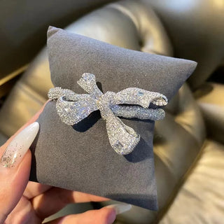 Empress Bow Bangle in 925 sterling silver, designed as a sculpted bow encrusted with white lab sapphires for a bold, couture-inspired look.
