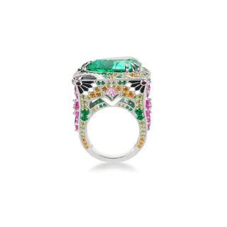 Side angle of A luxurious silver statement ring  featuring a large trillion-cut teal Paraiba gemstone at the center. The wide band is intricately adorned with pink, orange, green, and white gemstones in floral and geometric patterns, showcasing elaborate craftsmanship and vibrant color.