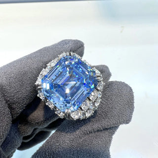 Majestic sterling silver cocktail ring featuring a large emerald-cut aquamarine centerpiece surrounded by lab-created sapphires, evoking the icy brilliance of glaciers and celestial light.